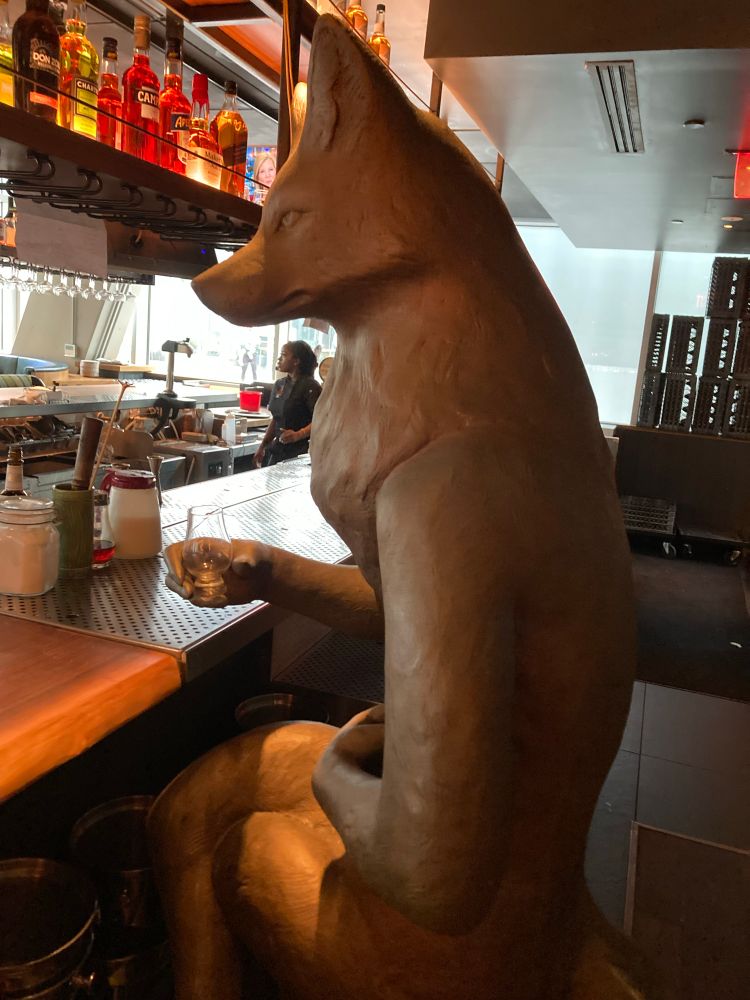 A large fox statue seated at a bar