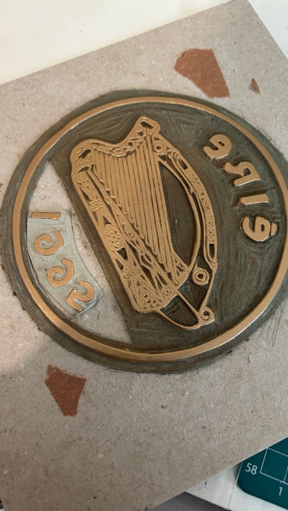 Carved linocut block depicting an old Irish coin with a harp, éire and the year 1995