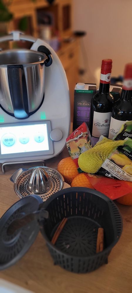 Rotwein, Traubensaft, Zitronen, Orangen  Zimtstangen, Nelken, im Hintergrund ein Thermomix 