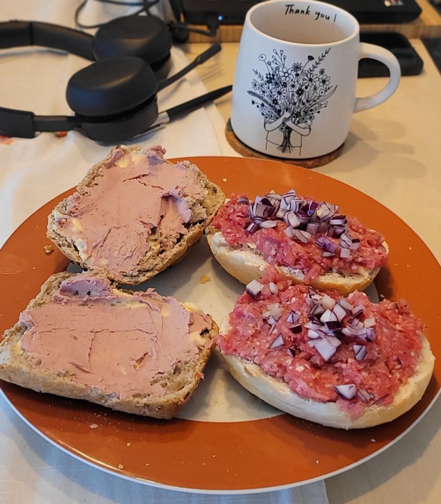 2 Gehacktesbrötchen mit Zwiebeln und 2 mit Leberwurst, dahinter eine Tasse mit Kaffee, mein Headset und der Laptop