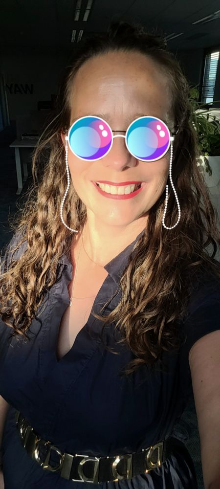 Selfie, ich lächle in die Kamera und trage roten Lippenstift, ein blaues Kleid, einen goldenen Gürtel, die Haare halb offen gelockt