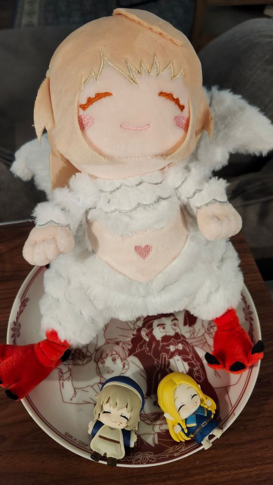 A plush of Chimera Falin and happily stuffed Tall Man Falin and Marcille sitting an a plate adorned with Senshi and Chilchuck