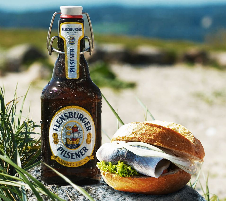 Flasche Flens & Fischbrötchen an einer Nordseedüne.