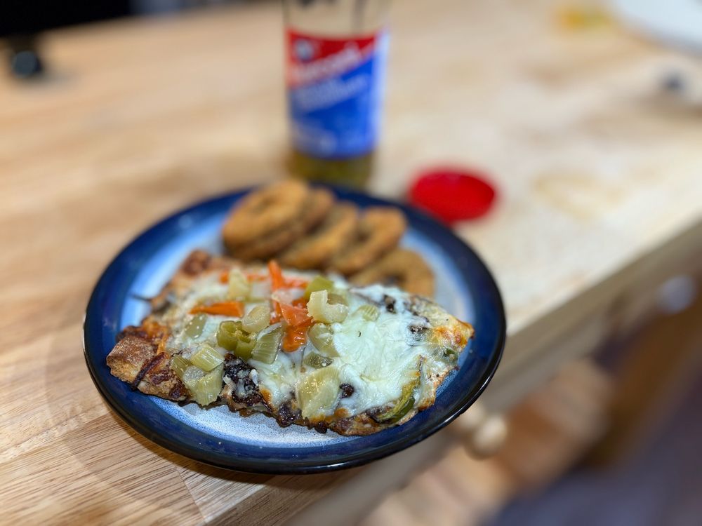 Unremarkable pizza with lots of Marconi giardiniera on top and some White Castle chicken rings. Also the iPhone focused really weird so it looks like the rest of the frame is a simulation of someone with a particular form of vision impairment from cataracts or macular degeneration. 