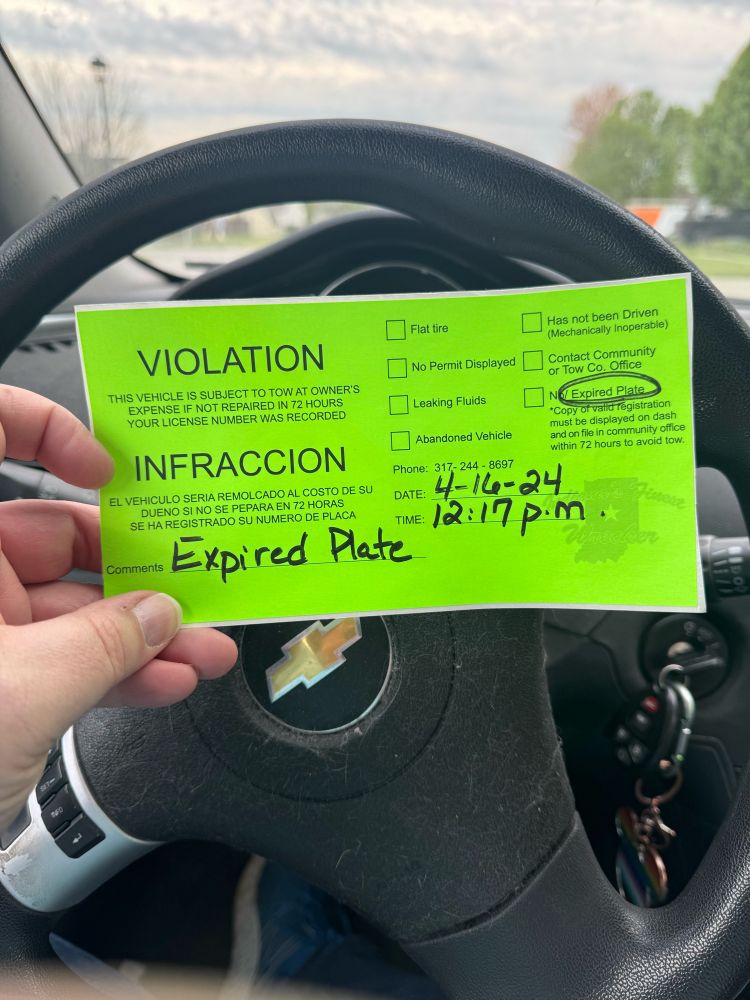 A sticker left under my wiper blade threatening towing for an expired plate.