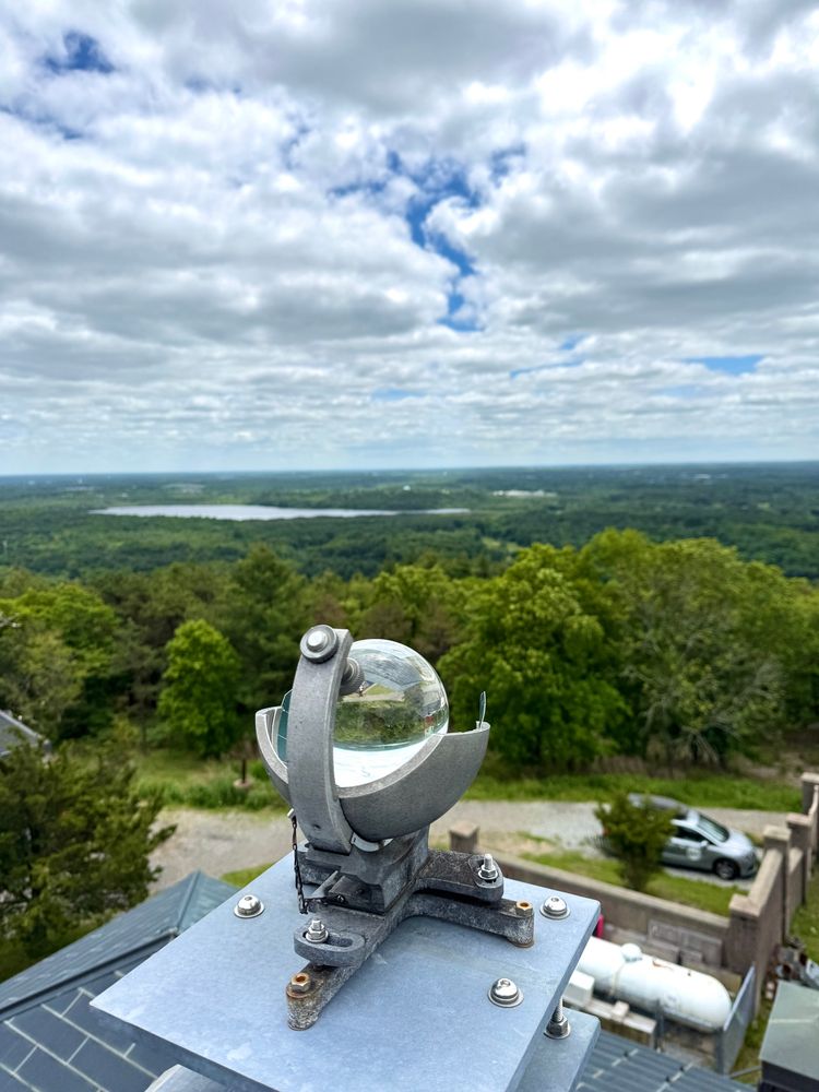 View from top of GBH Observatory with crystal ball of the Campbell-Stokes sunshine recorder in foreground & trees& pond far below in distance. 