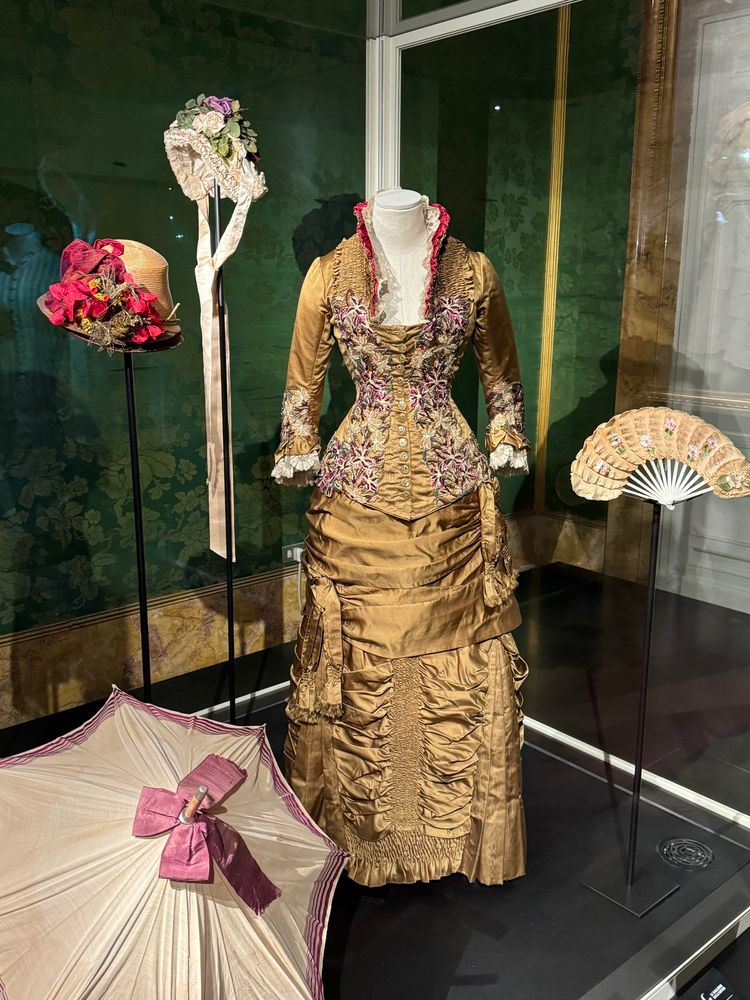 A gold dress with high color & tight bodice embroidered with magenta flowers (sorry--I seem to have not gotten the museum description!)