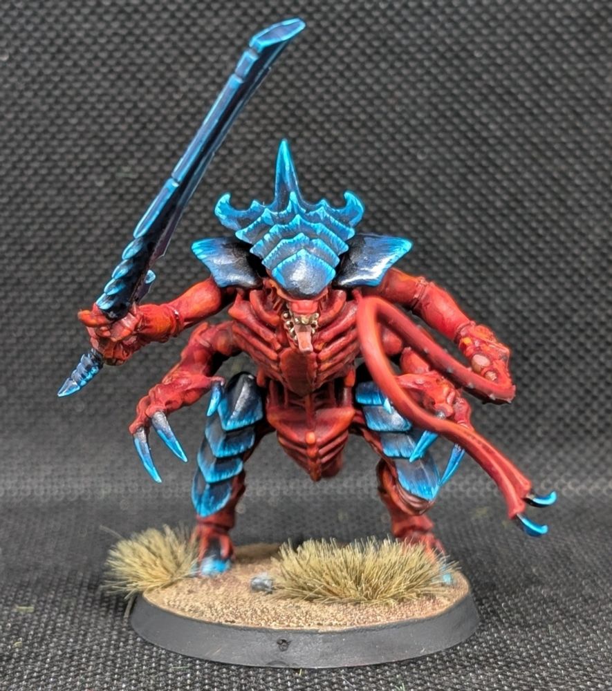 A Tyranid Warrior. He has a Lashwhip and Bonesword, plus Rending Claws. 

He is he is mainly red but with a Blue/Black Carapace in the style of hive fleet Behemoth. 