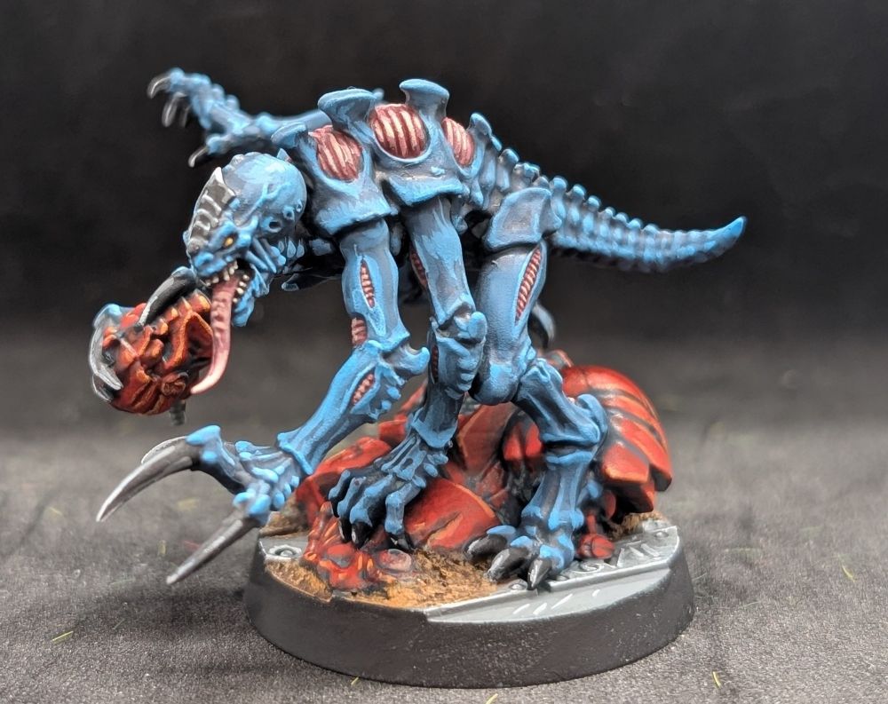 A Genestealer painted in the classic blue scheme crouched over a dead Blood Angels Terminator. 

The Genestealer seems rather happy with himself. 