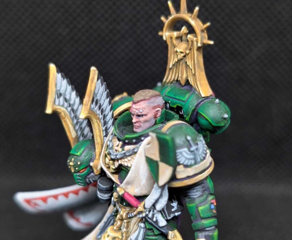 Close up of the upper part of the miniature, focus the head. 

Dark Angels Master Lazarus from Games Workshop. 

His armour is dark green, the inside of his cloak is white with red trim. His sword is Non-metalic silver and the trim of his armour is non-metalic gold. 

Painted by me. 