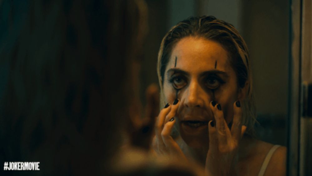 a woman is looking at her face in a mirror with the hashtag #jokermovie