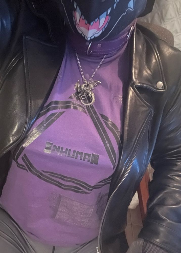 Dragoness wearing a purple Crowcorps therian t-shirt with a draconic amulet & a leather jacket over the top