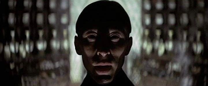 Still from The Devils (1971): a face dramatically lit from below, the background blurry and full of contrasting light.