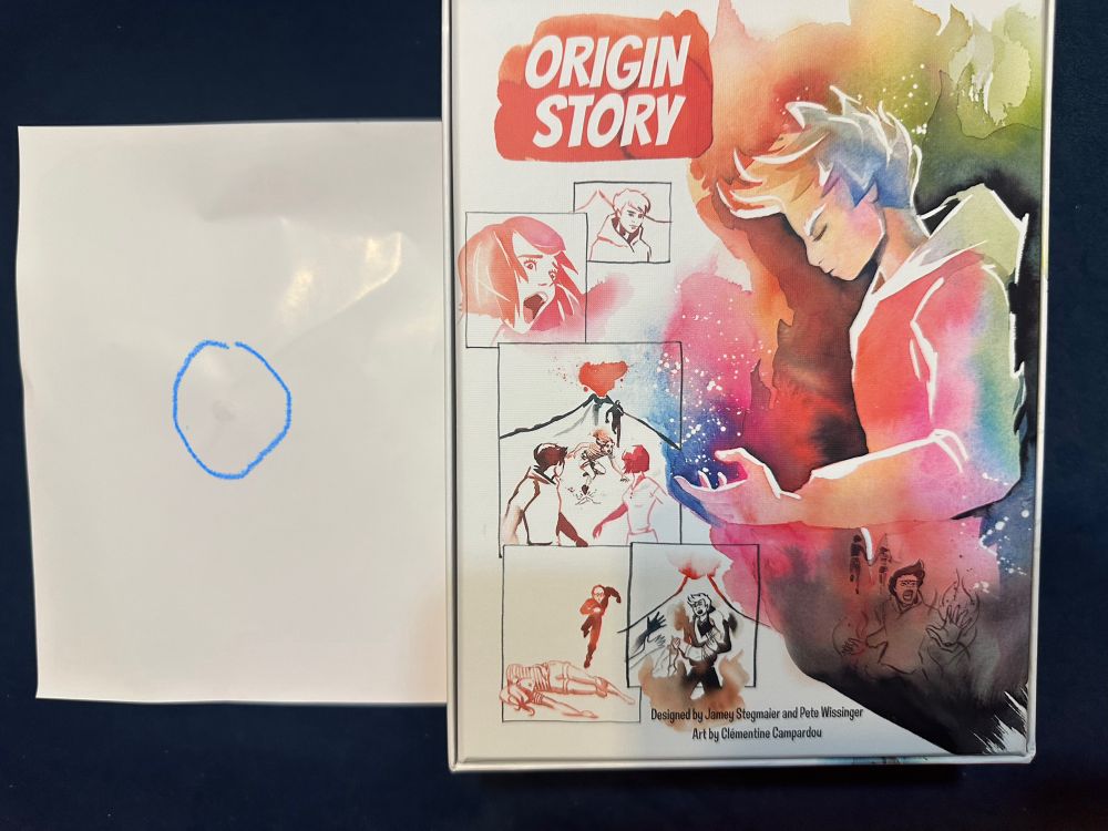 Back side of box with human wearing sweatshirt. No rip on box because hair dryer was used. Next to box is plain white backside of paper glued to box. Blue circle around gummy glue used to glue paper to back of box. 