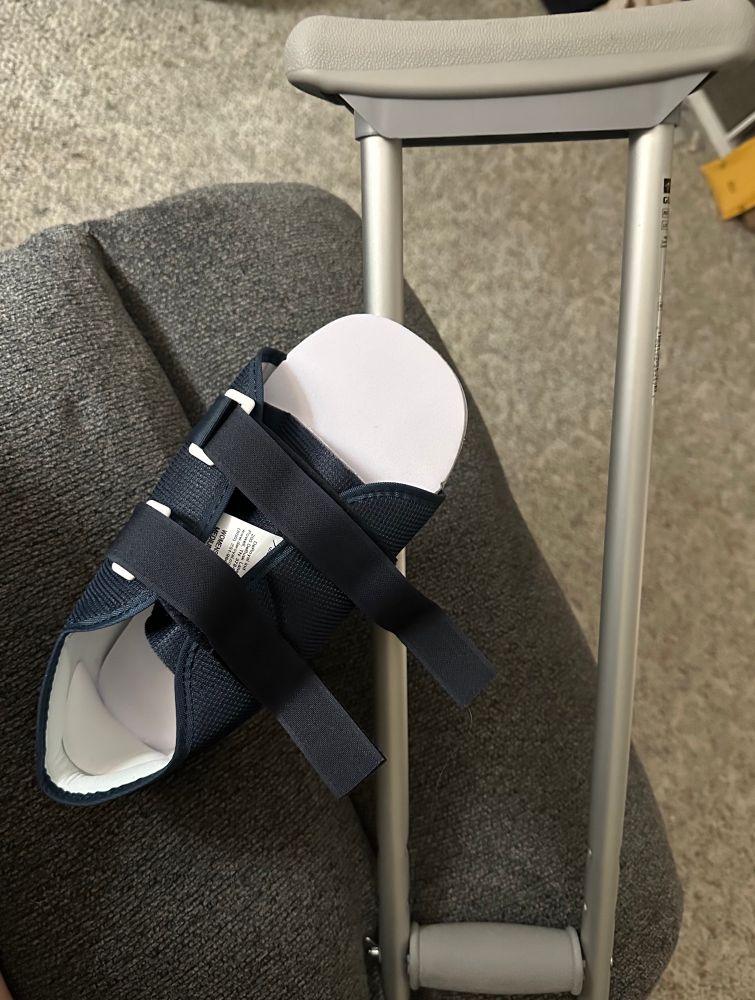 A boot for injured foot on top of a crutch. 