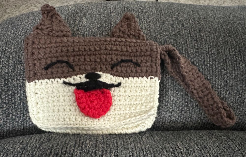 Dog wrist purse with tongue out. The tongue latches purse shut.