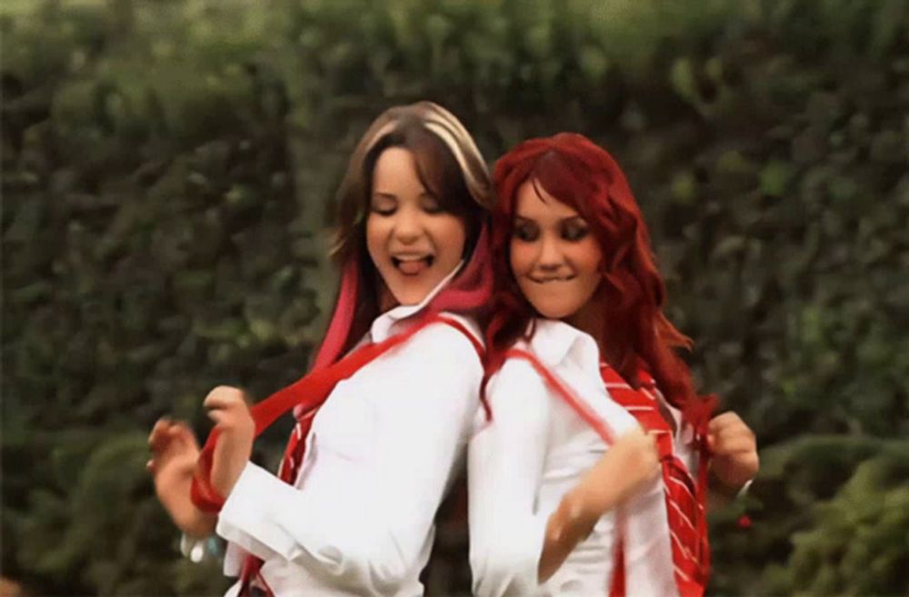 two women with red hair and white shirts are dancing together