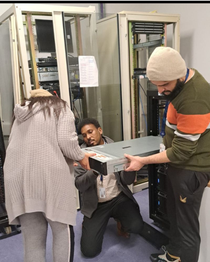 1 female and 2 male hold large computer equipment