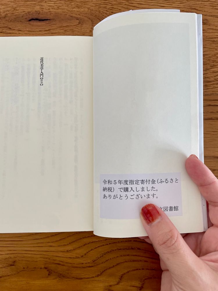 公立図書館で借りた書籍に「令和5年度指定寄付金（ふるさと納税）で購入しました。ありがとうございます」と書かれたシールが貼ってある