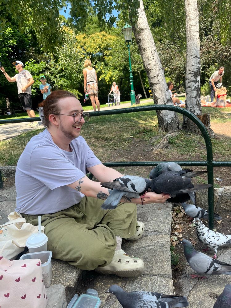 me sitting cross legged, holding out both hands and theres 3 pigeons sitting on my
hands