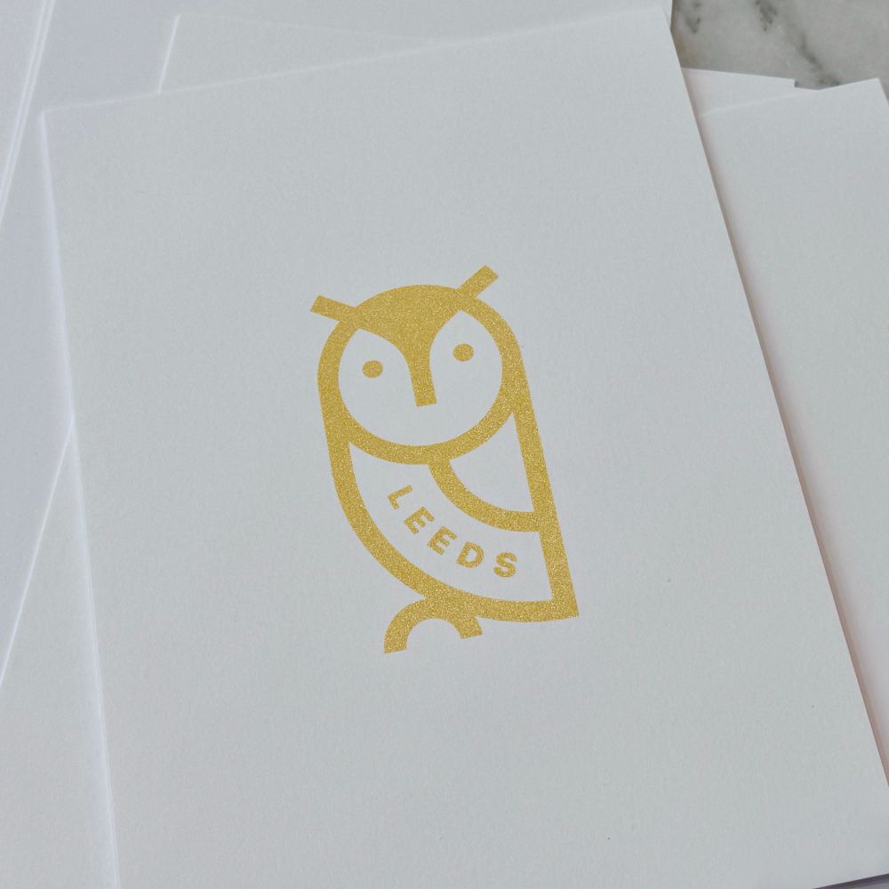 Gold printed owl on white paper.