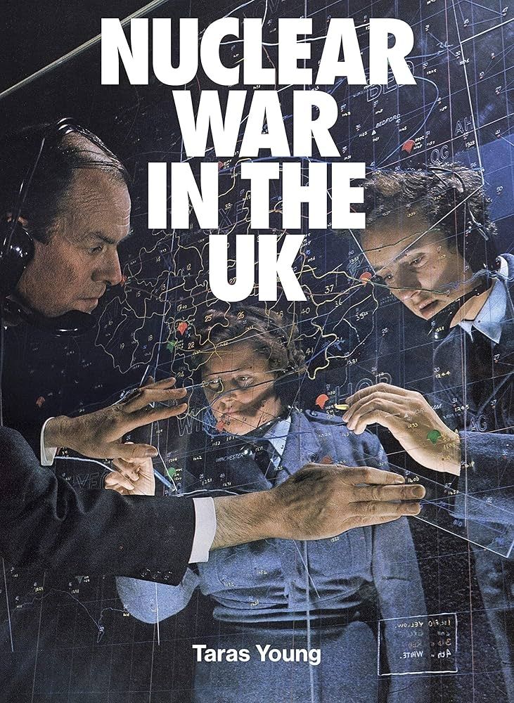Cover of book Nuclear War In the UK by Taras Young. Image shows 3 people plotting things on a map printed on acrylic and stood upright, a transparent wall. One person in front, two people behind. 