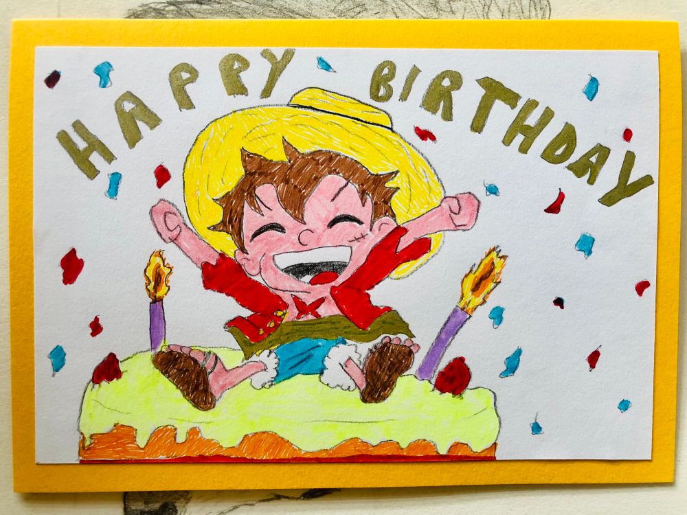 Hand-drawn birthday card on bright yellow background, featuring Luffy celebrating on top of a birthday cake with yellow frosting with 2 candles whilst confetti falls around him with Happy Birthday written in gold writing 