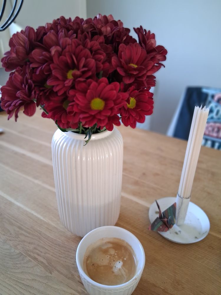 Ein Tisch mit Blumen in einer Vase, Kaffee und einer Kerze.