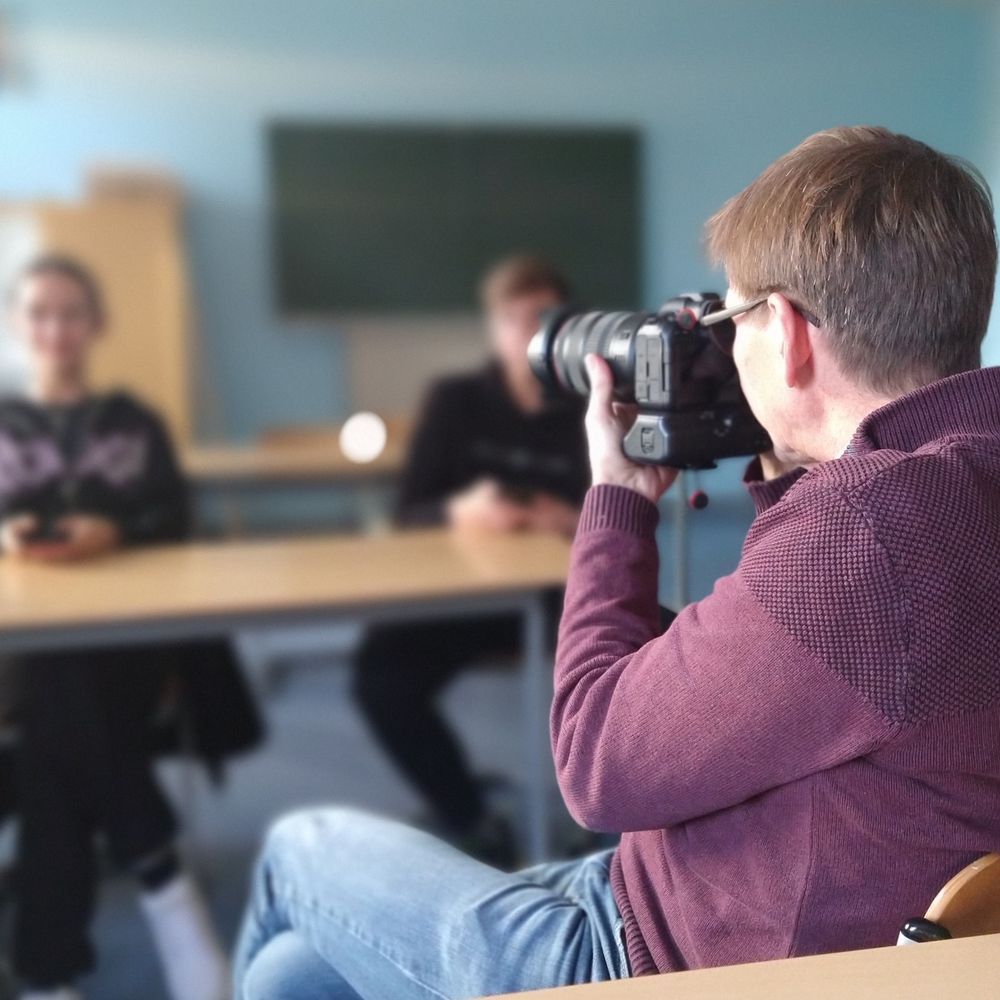 Mann fotografiert im Klassenraum.