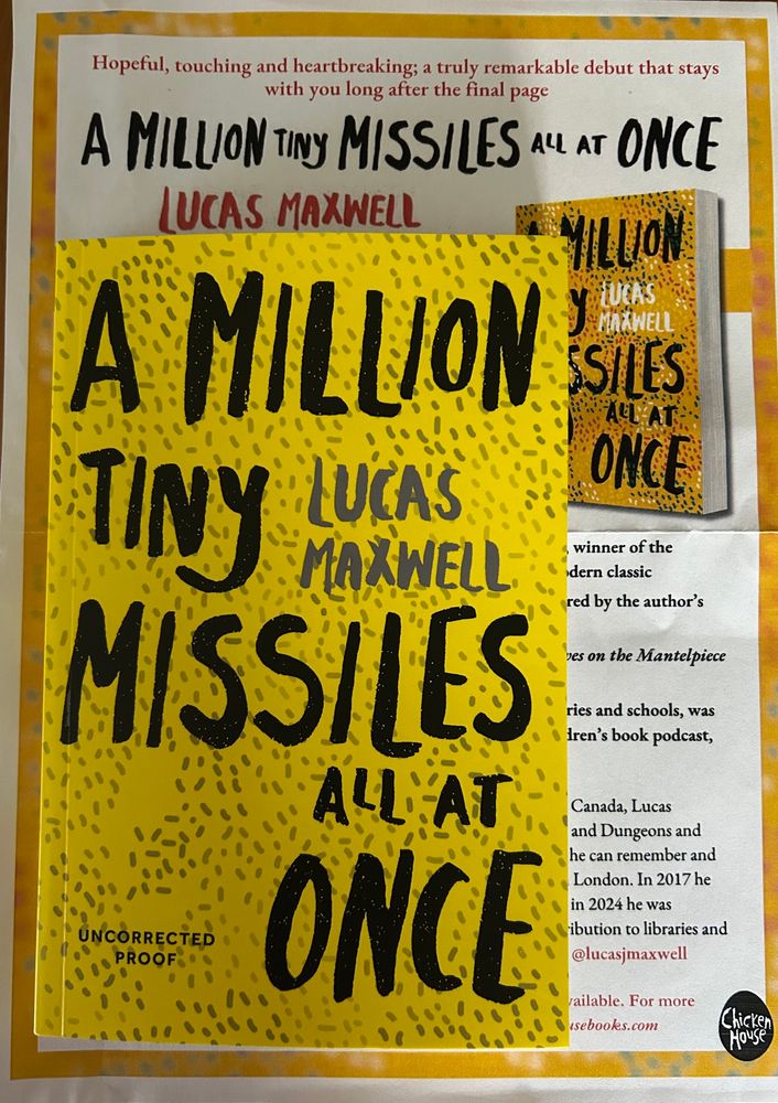 A paperback book which is mostly yellow with the title in large black letters taking up most of the space: A Million Tiny Missiles All At Once by Lucas Maxwell.