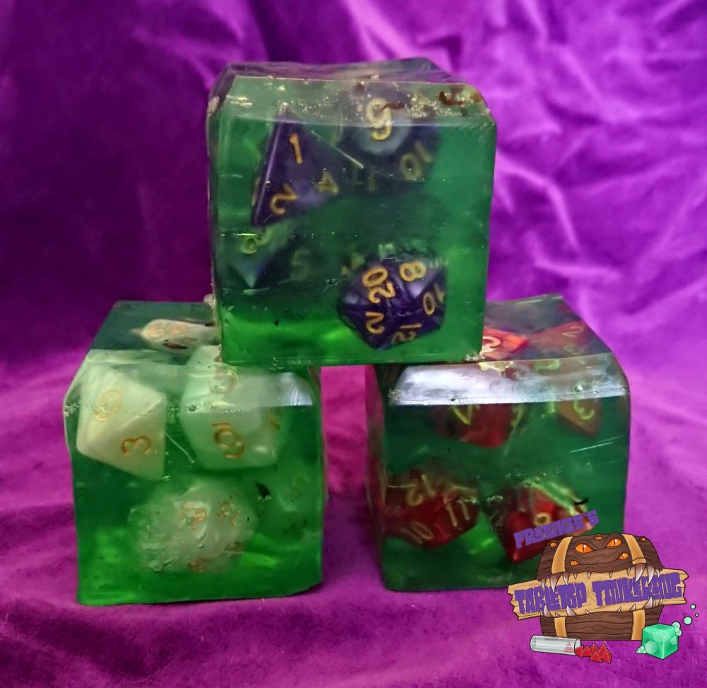 A stack of green translucent soap cubes with dice inside them. The three dice sets are purple, white and red