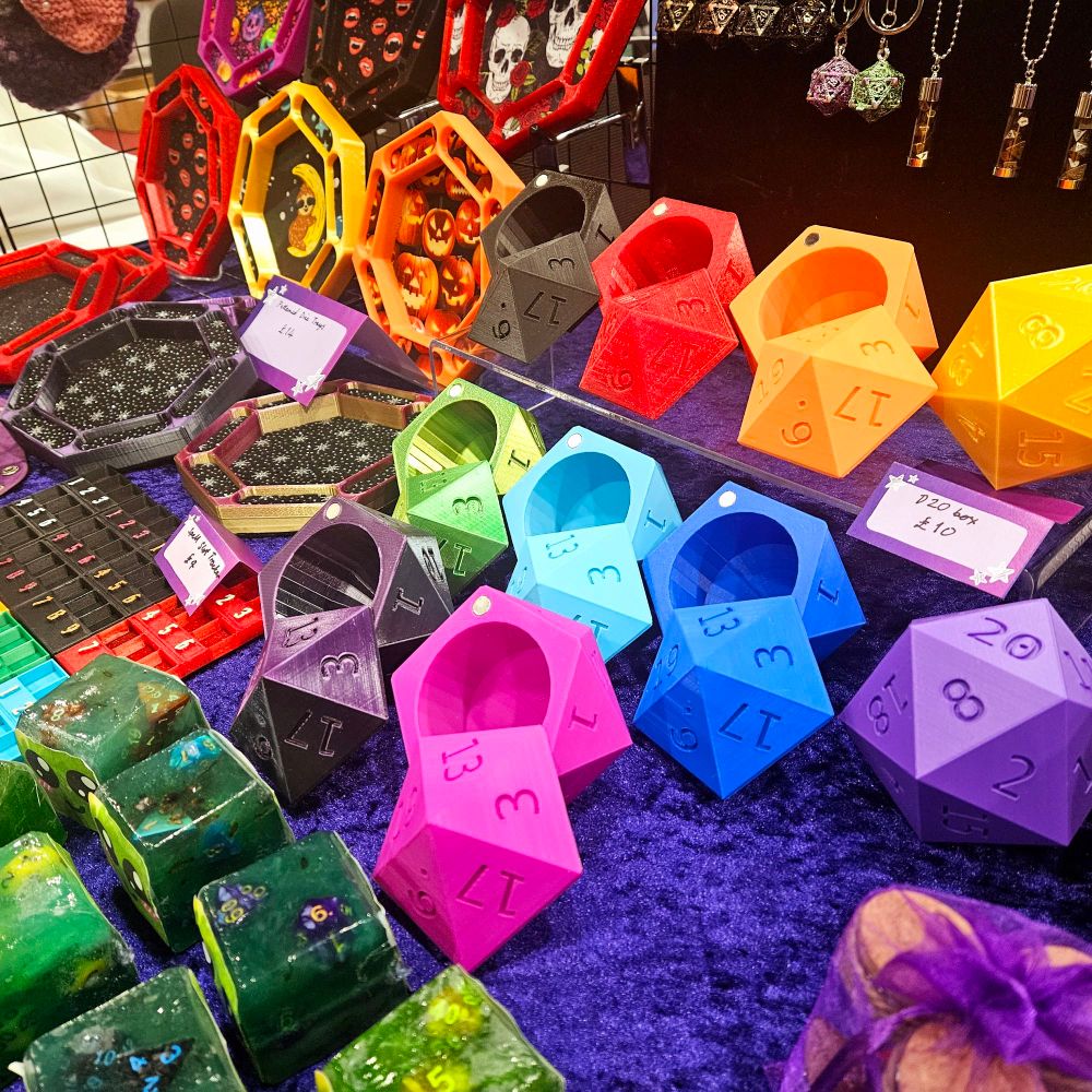 A selection of colourful ttrpg dice holders and soap on a purple table 