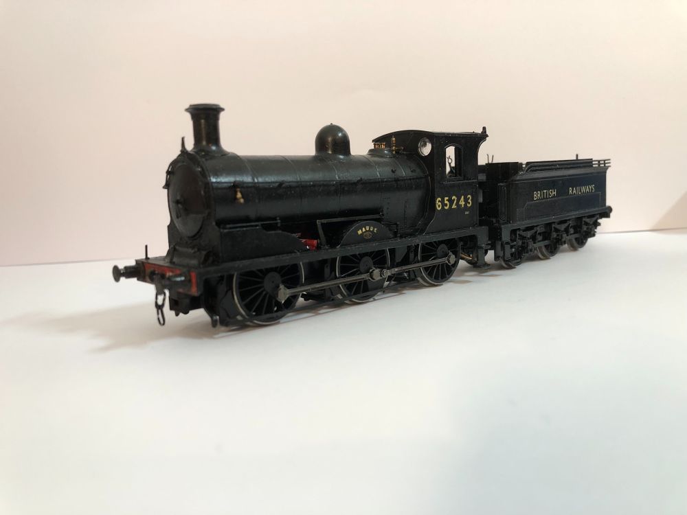 Angled view of a modified Hornby J36 model showing its left-hand side. It is painted a glossy black but is covered in dirt and grime. The tender shows signs of repairs with a long line of rivets cutting across the centre from back to front. Above this rivet line are the words 'BRITISH RAILWAYS' in the appropriate Gill Sans font in cream. The number '65243' adorns its cabside, also in Gill Sans (though the six has been modified to be curly) and in cream (note that the spacing is totally different to the other side! The name 'MAUDE' painted cream but NOT Gill Sans (WOWEE) and an LNER number plate are on the centre splasher. The bufferbeam is visible (though much of its detail is obscured by it's black painted buffers and buffer stocks) and is painted vermilion.