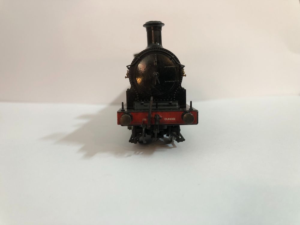 Front view of a modified Hornby J36 model showing its rgrubby bufferbeam. The front of the locomotive is painted a glossy black but is covered in dirt and grime - the bufferbeam is vermilion. The number shed name 'DUNDEE' (home of Dennis the Menace, Biffo the Bear, the Tay Bridge and cosins who love each other) is prominently displayed in white on the left of the bufferbeam (viewer's right). Barely legible is a microscopic 'J36' side of the bufferbeam. A screw-link coupling dangles in the centre of the bufferbeam - something that (yet again) Hornby should have provided themselves. Thank God for Bachmann spares!