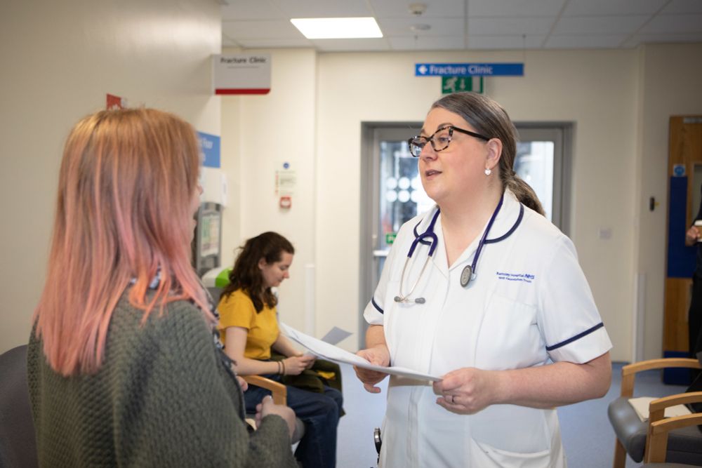 A photo of a woman talking to a medical professional in a hospital setting