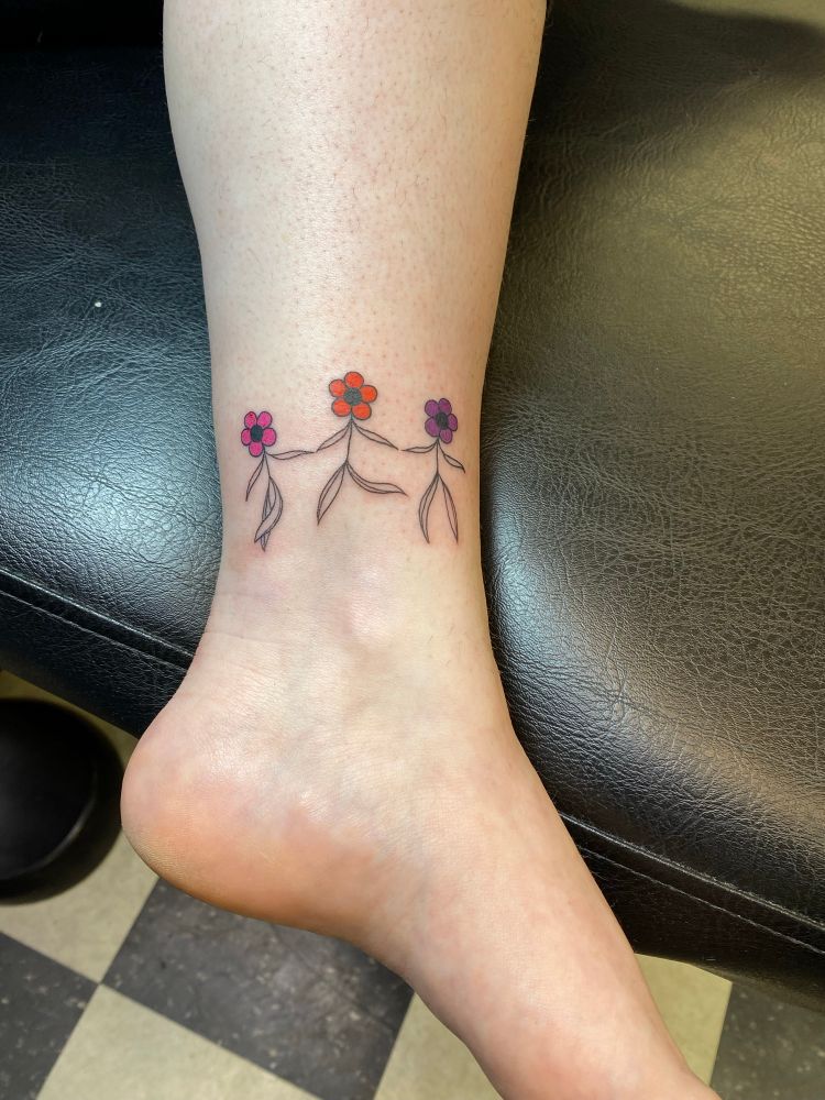 A picture of an ankle with three flowers holding hands and dancing