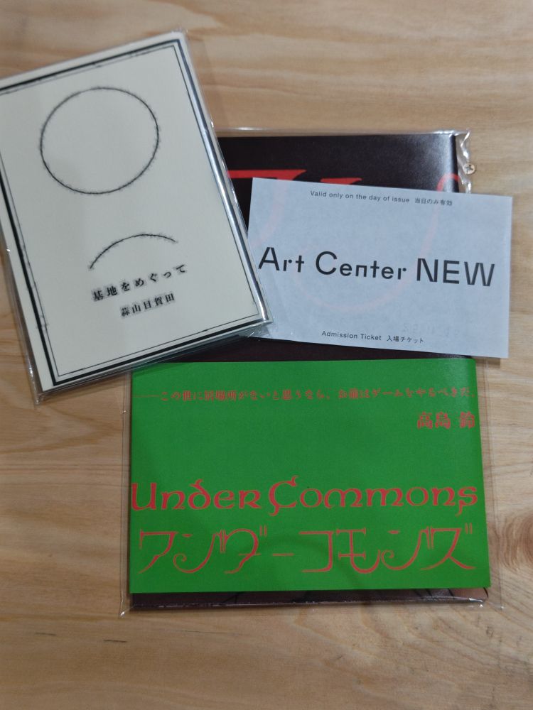 机の上にチケットや小冊子、折りたたまれた「アンダーコモンズ」のポスターが載せられている写真。