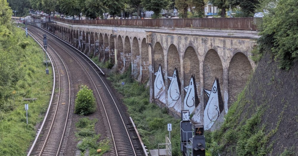 Four curious birds painted on a brick structure along a railroad track