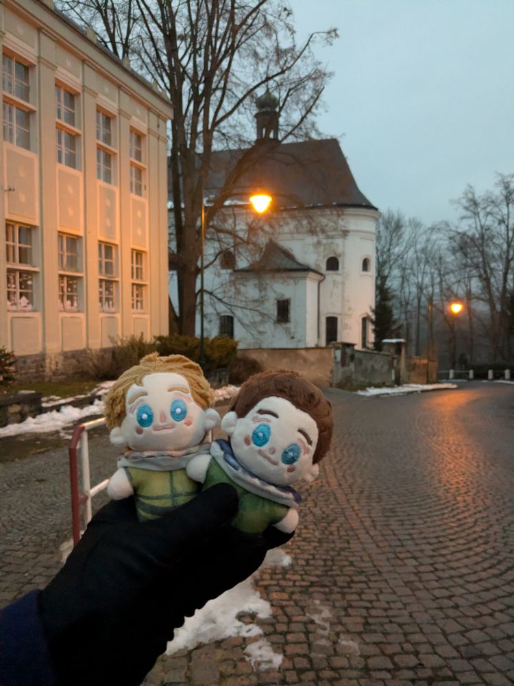 tiny plush Hans and Henry held in the foreground, with the Rattay Church in the background 