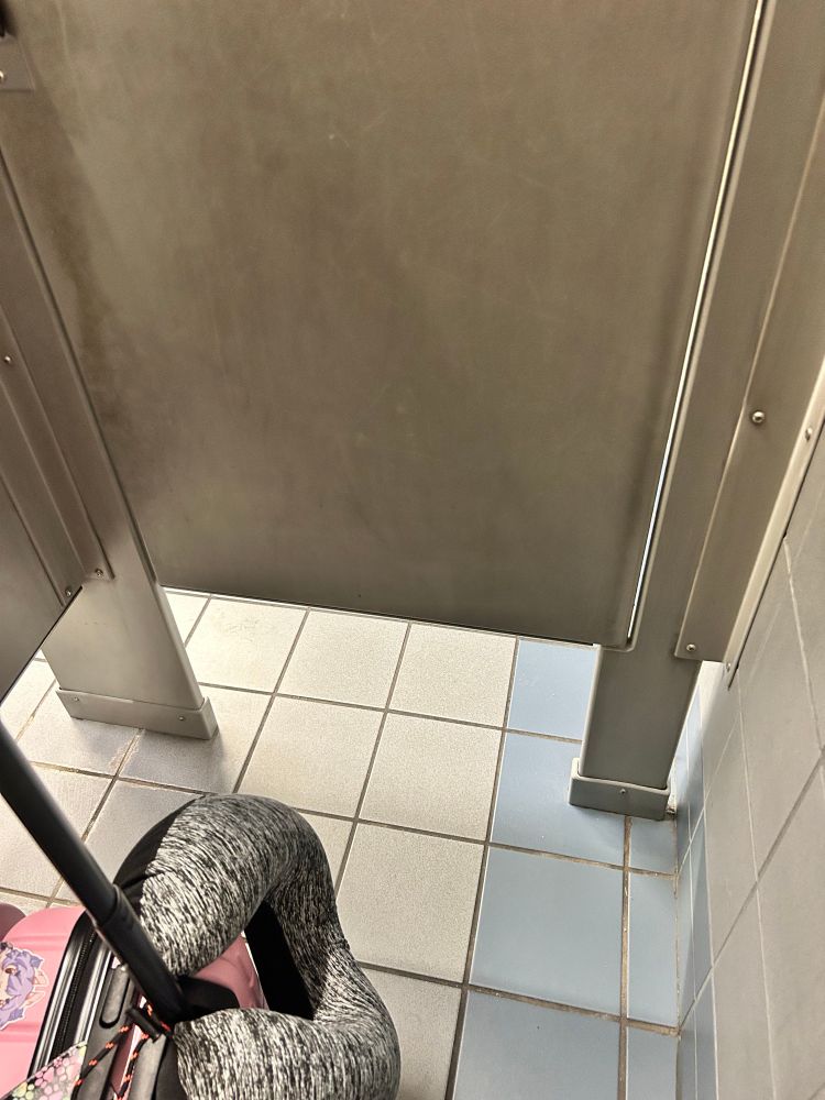American bathroom stall with a solid foot of wide open space between the floor and the bottom of the door