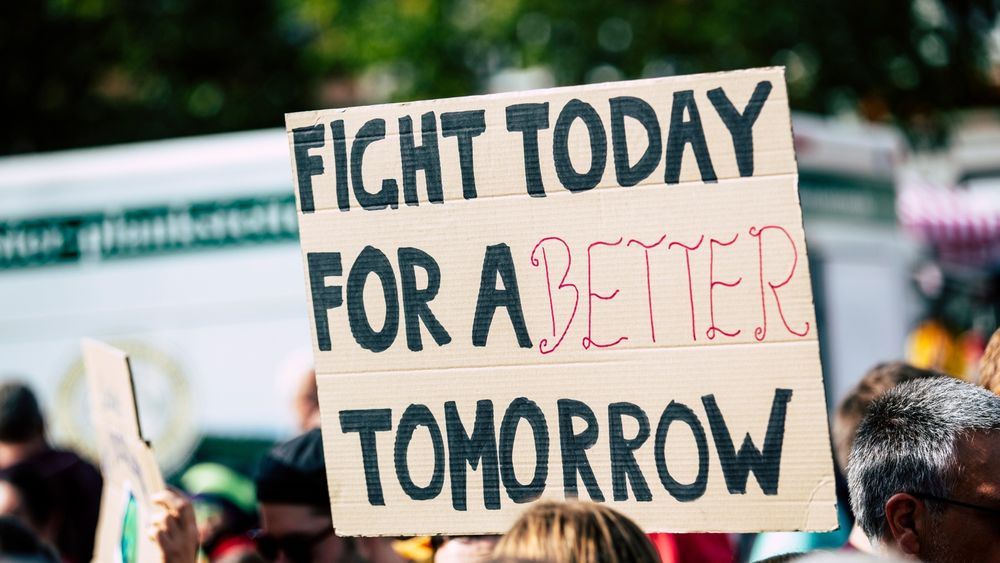 Someone holding a billboard saying 'fight today for a better tomorrow'