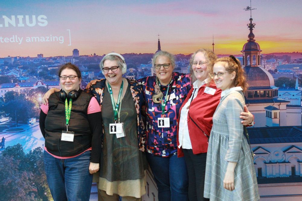Delegates smile in front of a backdrop of Vilnius