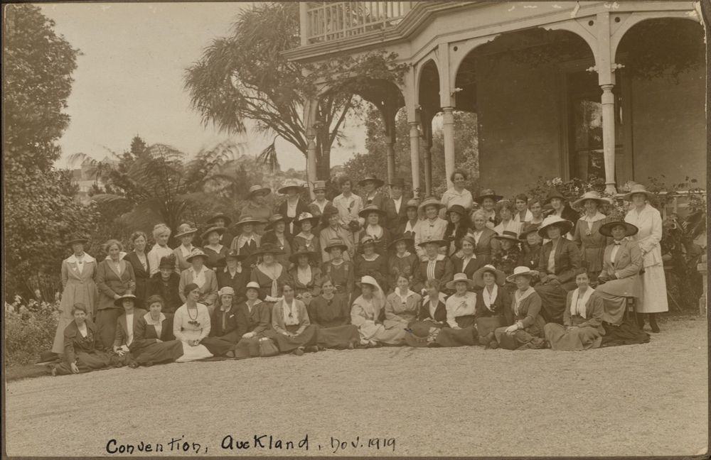 Alt: A photograph from 1919 of a group of women posed formally outside a two-storey house with a balcony. The occasion is the fifth triennial convention of the Australasian YWCAs, and the house is Hazelbank. Auckland Libraries Heritage Collections 318-Album-90-03-1. https://kura.aucklandlibraries.govt.nz/digital/collection/photos/id/68640