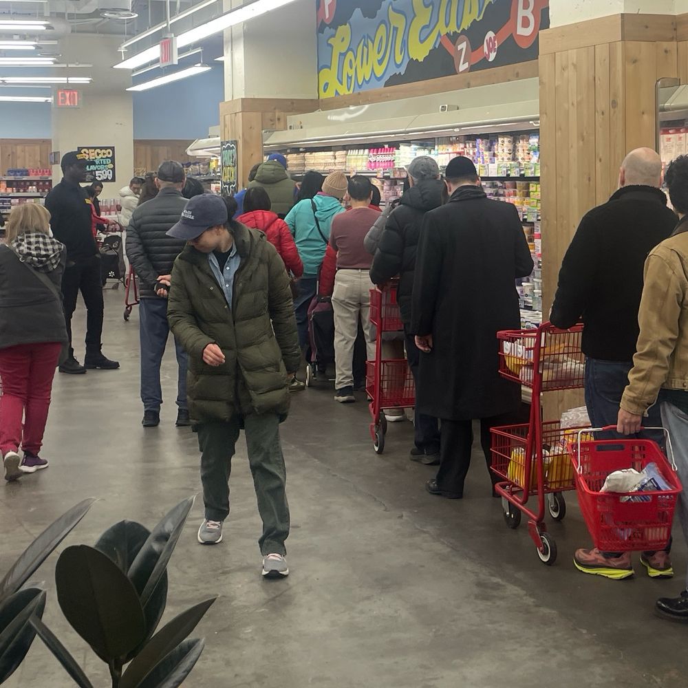 Line of people at the egg case, a security guard watching them