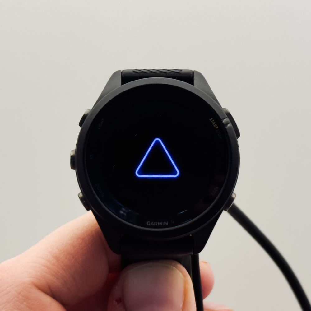 A close-up picture of a Garmin watch showing a blue triangle, a symbol they seem to use to indicate critical errors.