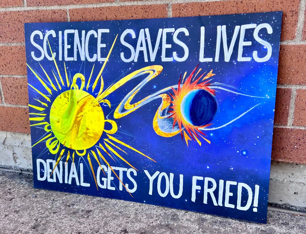 poster that reads “Science Saves Lives, Denial gets you fried!” with an image of the Sun hitting the Earth with a CME.