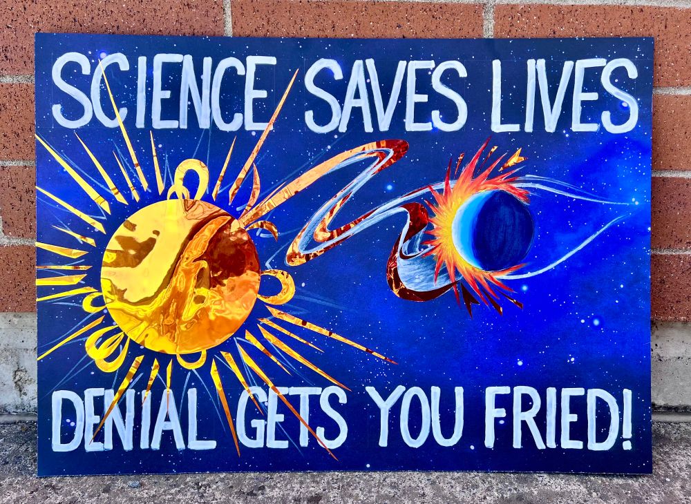 poster that reads “Science Saves Lives, Denial gets you fried!” with an image of the Sun hitting the Earth with a CME.