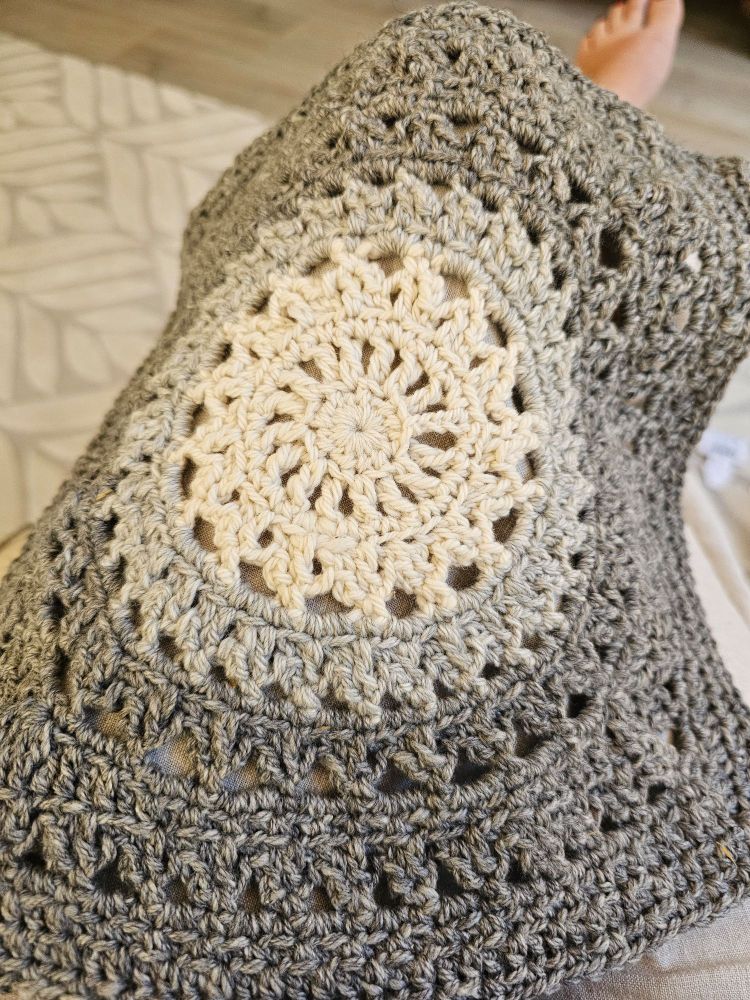 Large granny square made with cream, light grey and dark grey wool and alpaca yarn. The shapes are sun-like. 