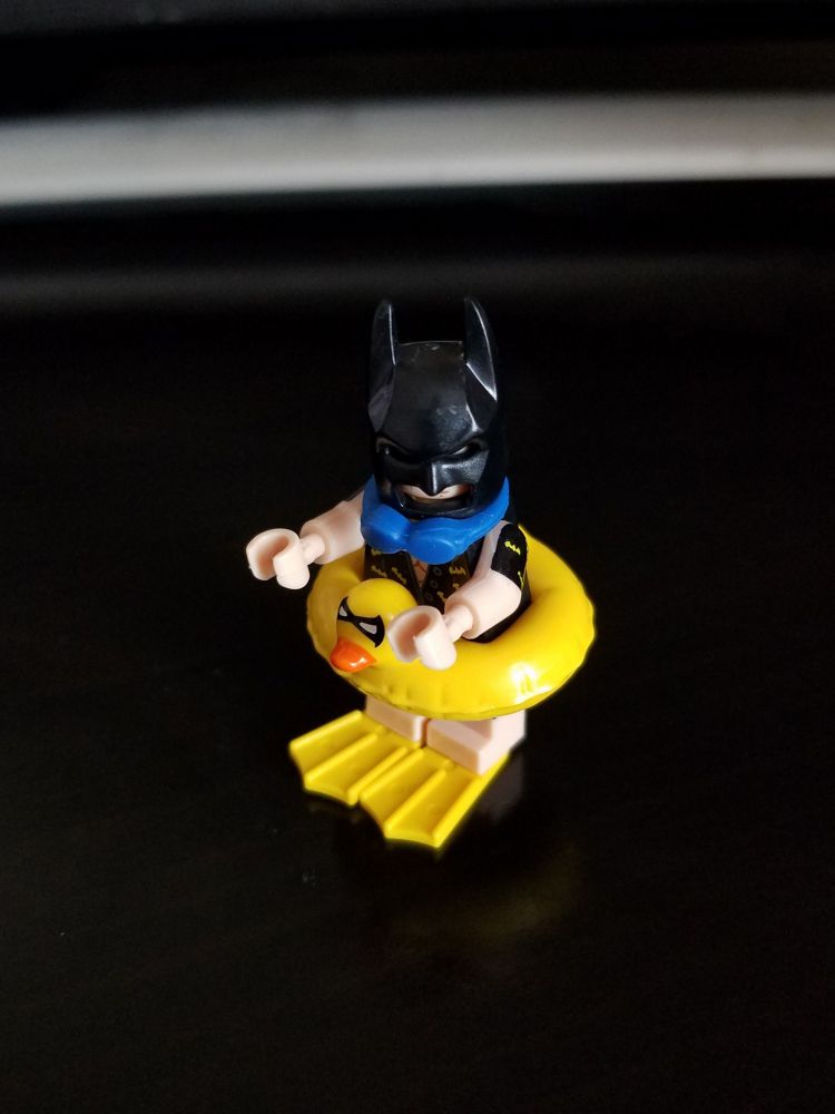 LEGO Batman in a swimsuit with goggles, flippers, and a duck floaty.