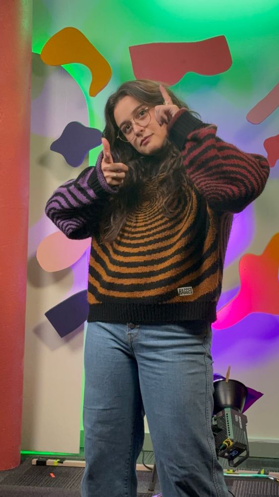Host/Resident Madelyn Leembruggen posing with finger guns on the SciShow set. 